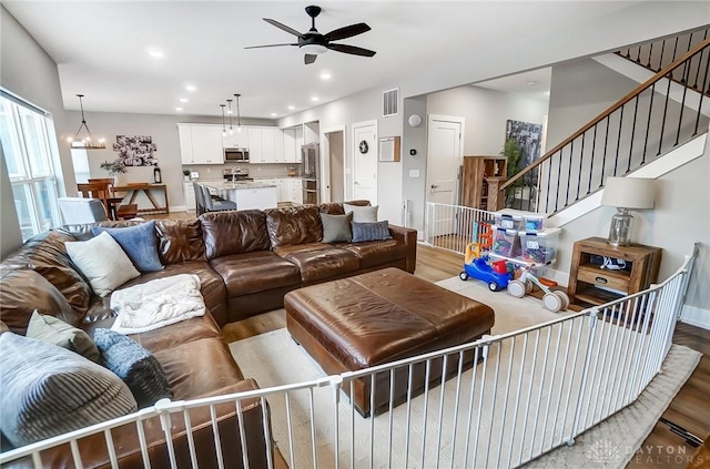 living room with hardwood / wood-style floors and ceiling fan with notable chandelier