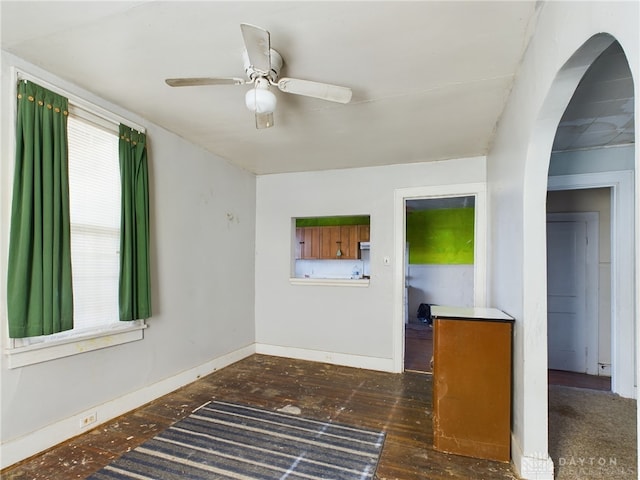 empty room featuring a ceiling fan, dark wood-type flooring, and baseboards