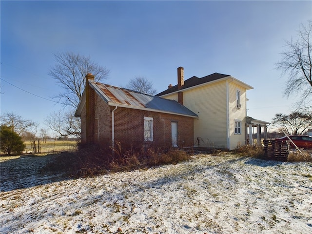 view of side of home featuring a chimney and brick siding