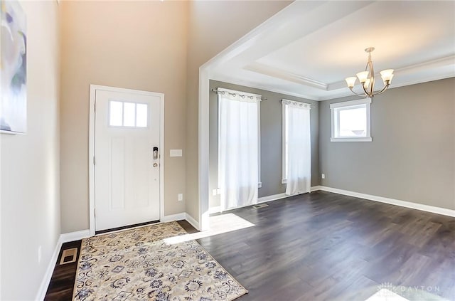 entryway featuring a chandelier, a raised ceiling, and dark wood-type flooring