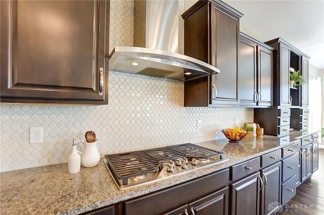 kitchen featuring wall chimney exhaust hood, dark hardwood / wood-style flooring, dark brown cabinetry, and stainless steel gas cooktop