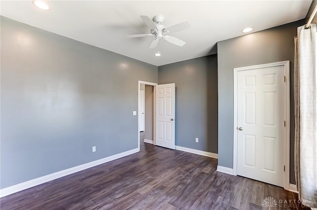 unfurnished bedroom with ceiling fan and dark wood-type flooring