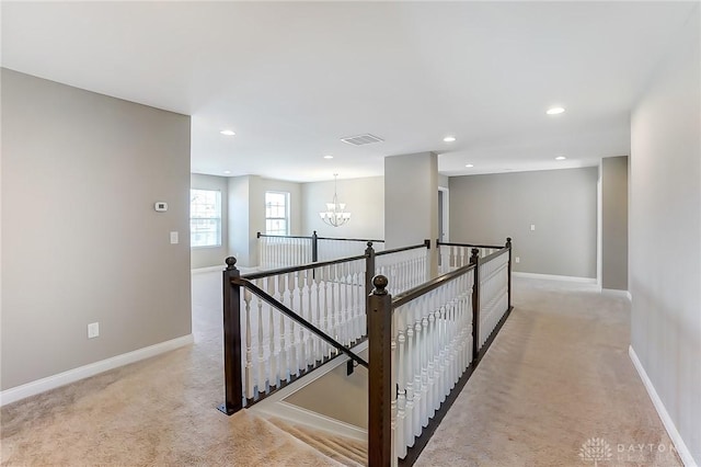 hall with light colored carpet and a notable chandelier