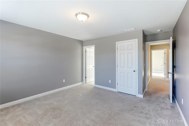 unfurnished bedroom featuring a closet and light colored carpet