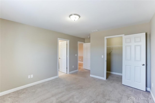 unfurnished bedroom featuring light carpet, a closet, and a spacious closet