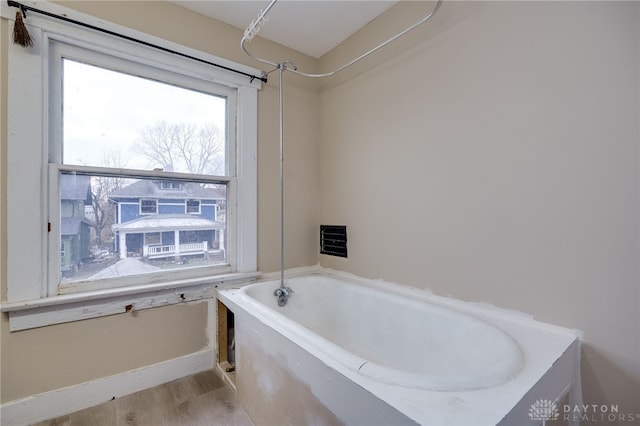 bathroom featuring wood-type flooring and a tub to relax in