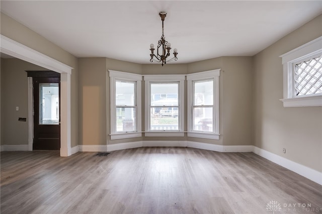 unfurnished dining area with light hardwood / wood-style floors and an inviting chandelier