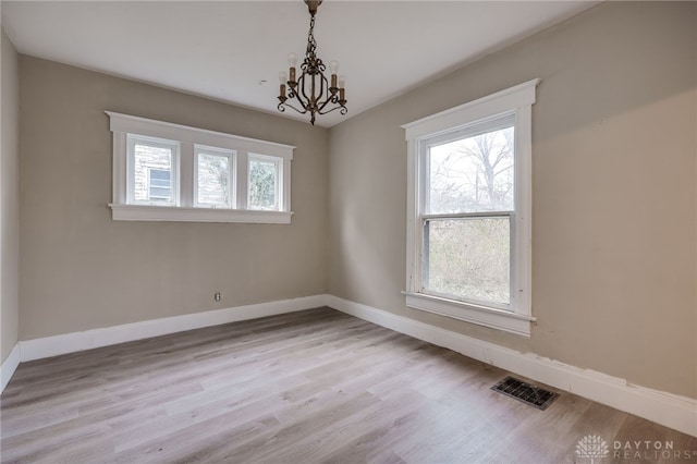 unfurnished room featuring light hardwood / wood-style floors and an inviting chandelier