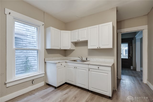 kitchen featuring white cabinets, light wood-type flooring, and sink