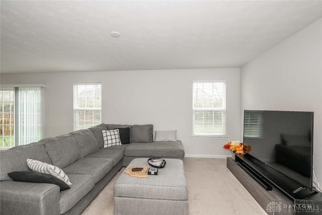 living room featuring a textured ceiling, plenty of natural light, and light carpet