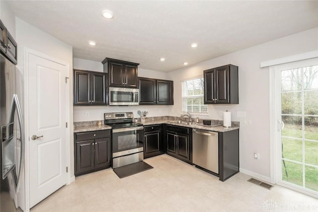 kitchen with light stone countertops, a healthy amount of sunlight, sink, and stainless steel appliances