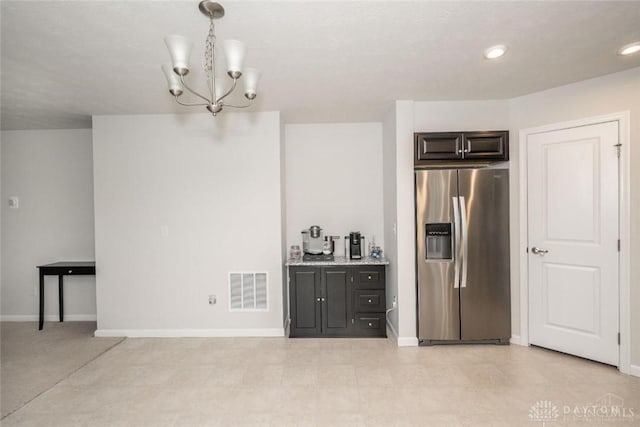 kitchen featuring a chandelier, stainless steel refrigerator with ice dispenser, light stone counters, and hanging light fixtures