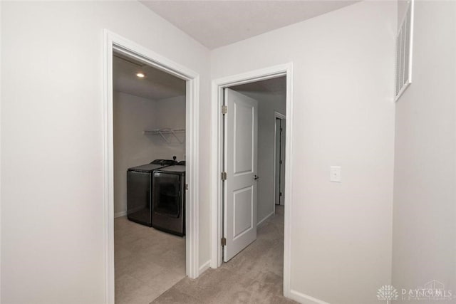 hallway featuring washer and dryer and light carpet