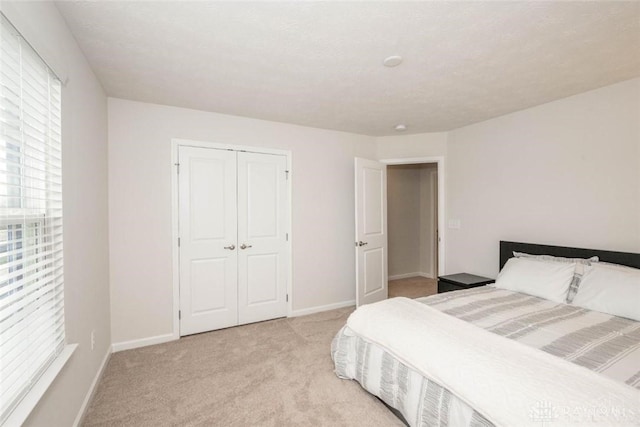 bedroom with light carpet, a textured ceiling, and a closet