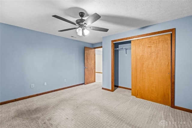 unfurnished bedroom with a closet, a textured ceiling, light colored carpet, and ceiling fan