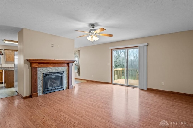 unfurnished living room featuring ceiling fan, a textured ceiling, and light hardwood / wood-style flooring