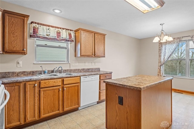 kitchen featuring white dishwasher, sink, pendant lighting, a chandelier, and a center island