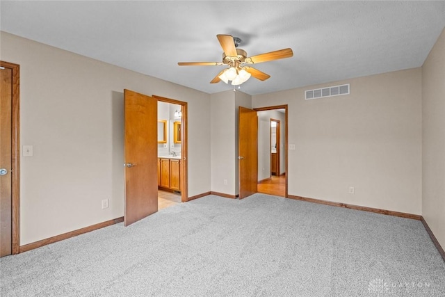 unfurnished bedroom featuring light carpet, ensuite bath, and ceiling fan