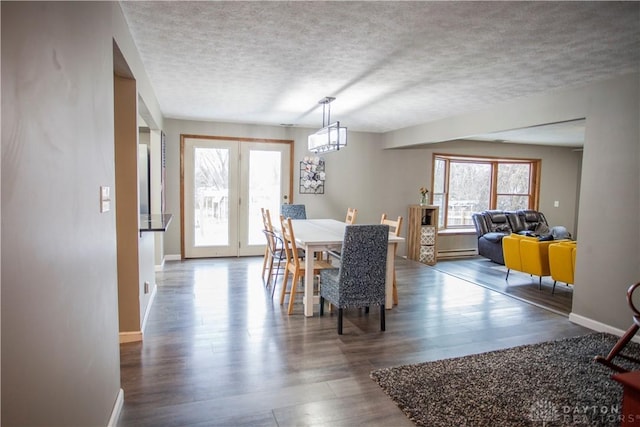 dining area with french doors, a textured ceiling, a baseboard heating unit, an inviting chandelier, and dark hardwood / wood-style floors