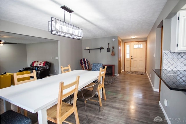 dining room featuring ceiling fan, dark wood-type flooring, and a textured ceiling