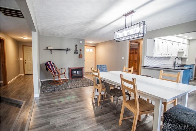 dining room with sink, dark wood-type flooring, and a textured ceiling