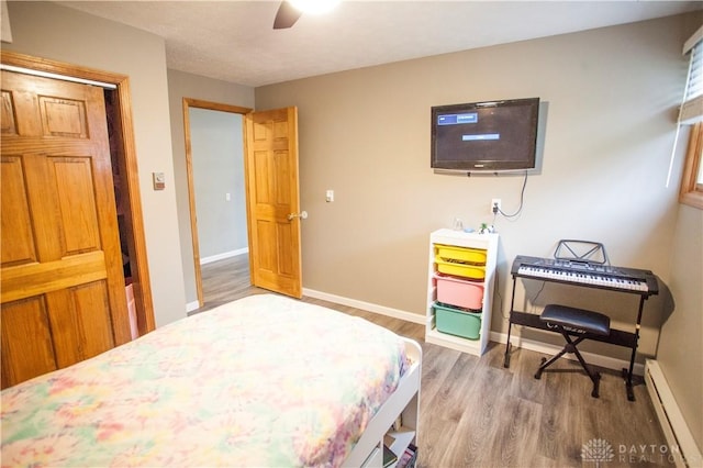 bedroom with ceiling fan, a baseboard radiator, and hardwood / wood-style flooring