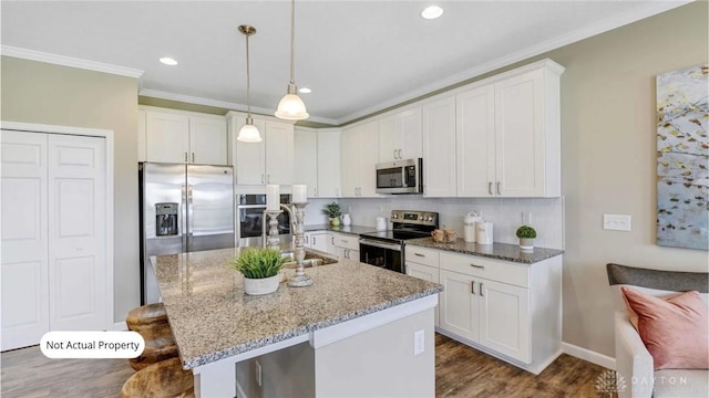 kitchen featuring a kitchen bar, white cabinetry, decorative light fixtures, and appliances with stainless steel finishes