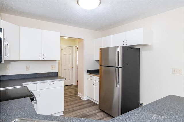 kitchen featuring hardwood / wood-style floors, stainless steel fridge, white cabinets, and a textured ceiling