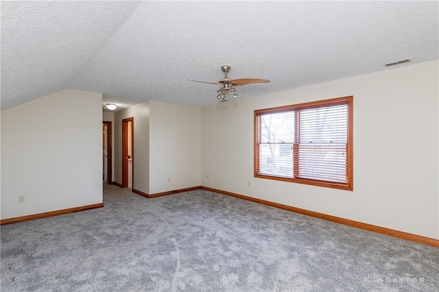 spare room featuring light colored carpet, a textured ceiling, and vaulted ceiling