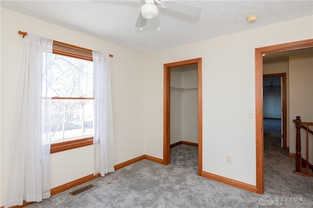 unfurnished bedroom featuring ceiling fan, light colored carpet, a spacious closet, and a closet