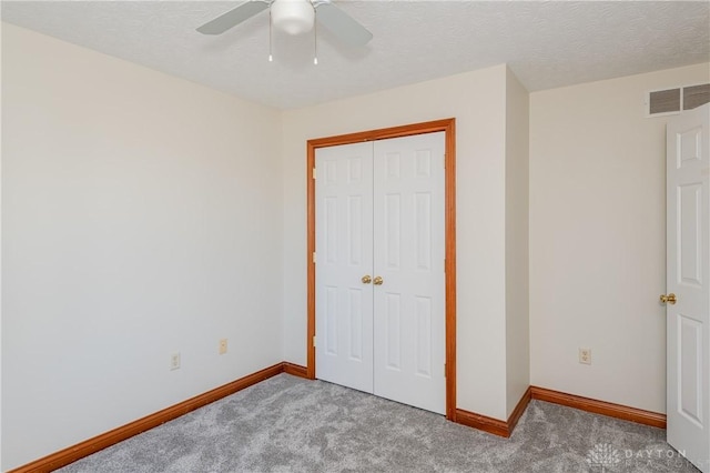 unfurnished bedroom with ceiling fan, carpet floors, a textured ceiling, and a closet