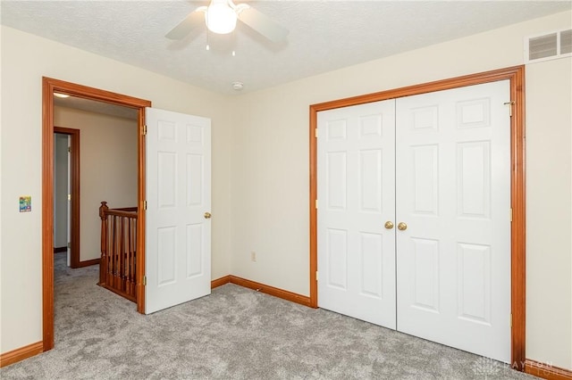 unfurnished bedroom with ceiling fan, light colored carpet, a textured ceiling, and a closet