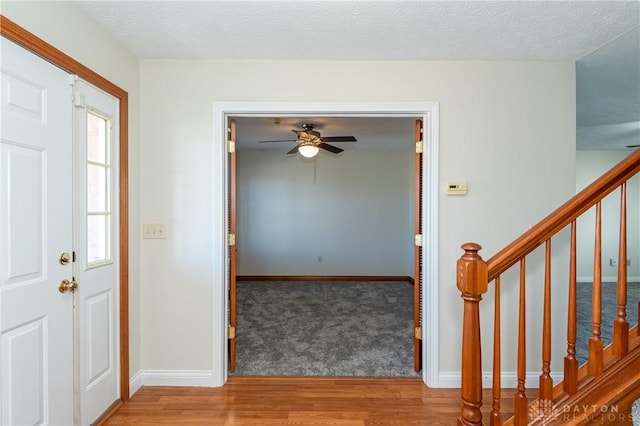 foyer with ceiling fan, wood-type flooring, and a textured ceiling