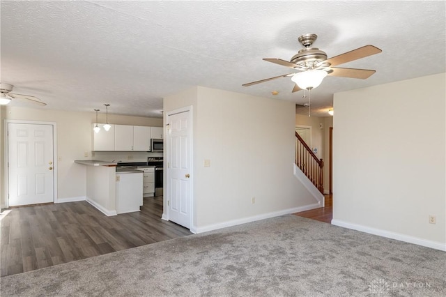 unfurnished living room featuring ceiling fan, dark hardwood / wood-style flooring, and a textured ceiling