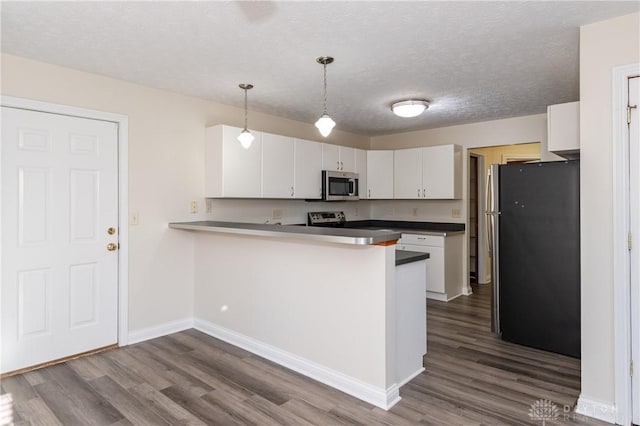 kitchen featuring pendant lighting, wood-type flooring, kitchen peninsula, white cabinetry, and stainless steel appliances