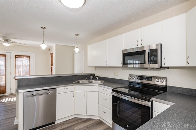 kitchen with white cabinetry, sink, stainless steel appliances, dark hardwood / wood-style flooring, and decorative light fixtures