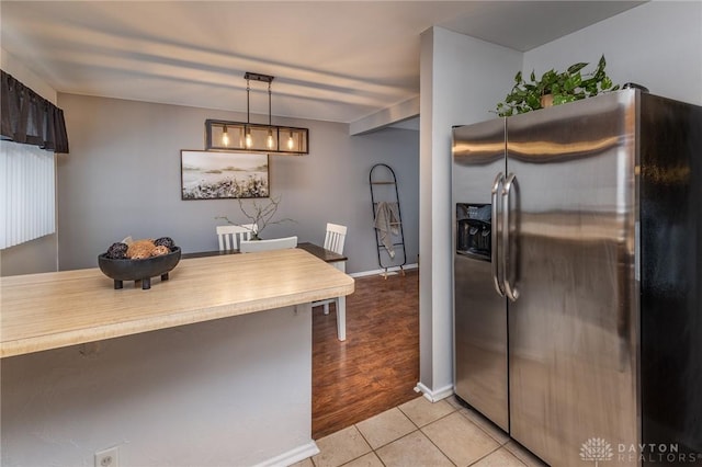 kitchen featuring hanging light fixtures, light tile patterned floors, and stainless steel refrigerator with ice dispenser