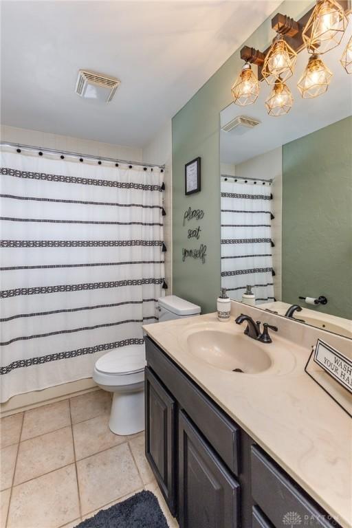 bathroom with toilet, vanity, tile patterned flooring, and curtained shower