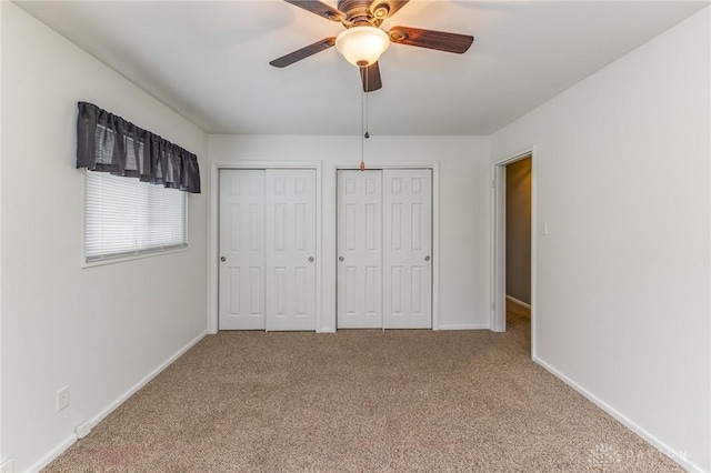 unfurnished bedroom featuring ceiling fan, carpet flooring, and two closets