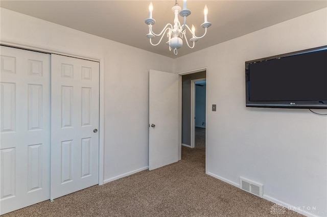 unfurnished bedroom featuring carpet flooring, a closet, and an inviting chandelier