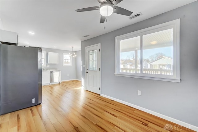 kitchen featuring ceiling fan with notable chandelier, decorative light fixtures, white cabinets, light hardwood / wood-style floors, and stainless steel appliances