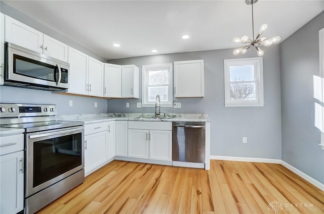 kitchen featuring stainless steel appliances, decorative light fixtures, and white cabinets