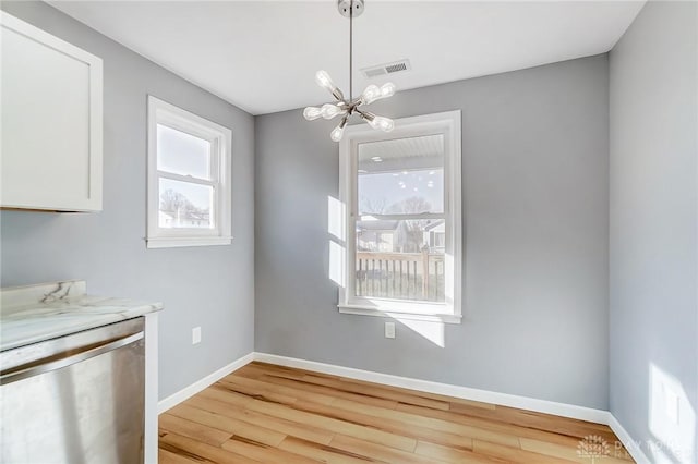 unfurnished dining area with an inviting chandelier and light wood-type flooring