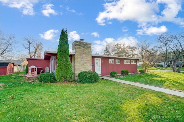 exterior space with a lawn, a chimney, and an outdoor structure