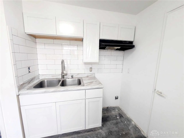 kitchen featuring white cabinets, a sink, light countertops, under cabinet range hood, and backsplash