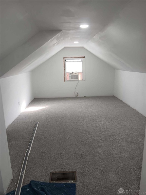 additional living space featuring vaulted ceiling, carpet floors, cooling unit, and visible vents