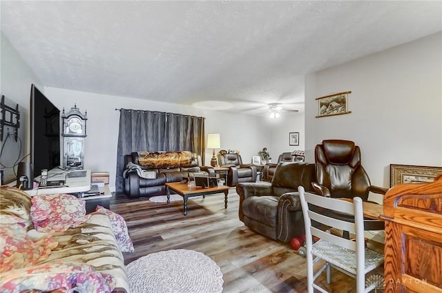 living room with ceiling fan, wood-type flooring, and a textured ceiling