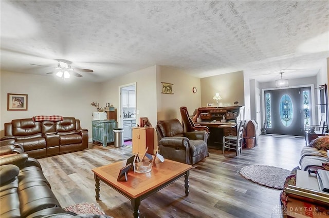 living room featuring ceiling fan, wood-type flooring, and a textured ceiling