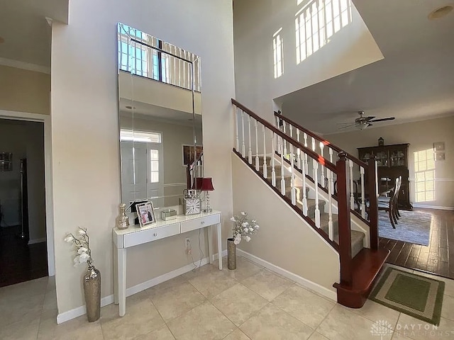 stairway featuring ceiling fan, plenty of natural light, ornamental molding, and hardwood / wood-style flooring