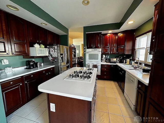 kitchen featuring a kitchen island, white appliances, sink, and light tile patterned floors